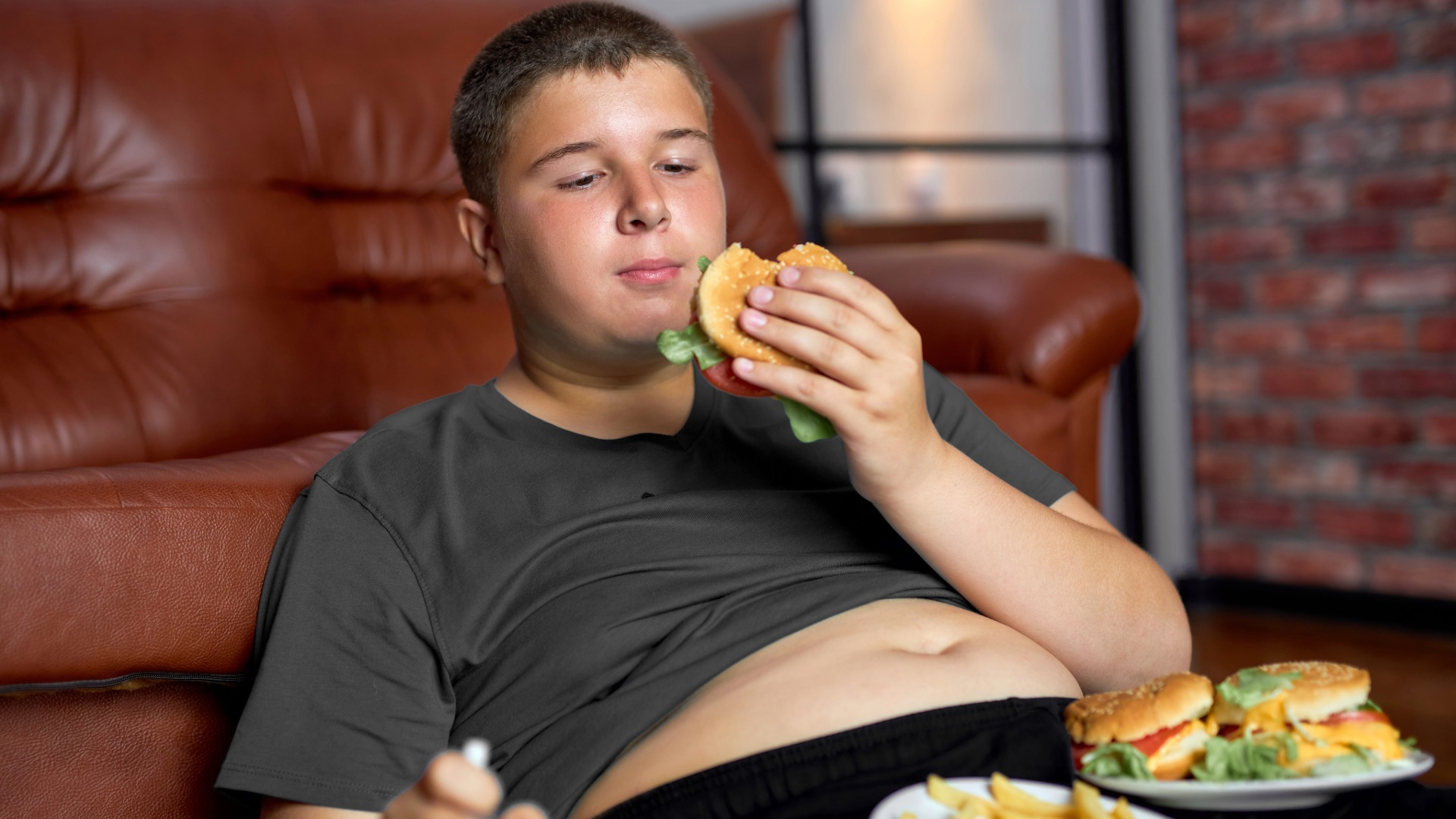 Niño obeso comiendo hamburguesa