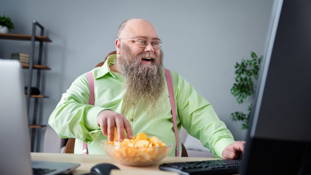 Hombre anciano mirando el ordenador y comiendo